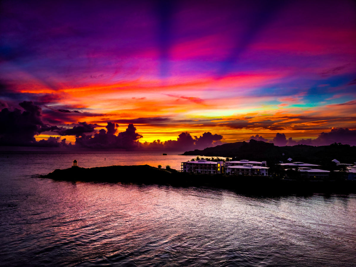 Cinematic sunset over ocean coast with vibrant purple and orange clouds over a coastal resort.
